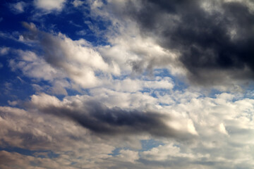 Blue sky with sunlight and dark clouds