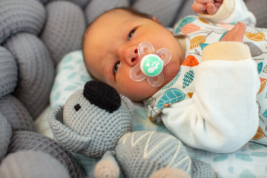 Neugeborener Junge im Bett mit Kuscheltier