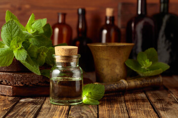 Fresh spearmint leaves and a small bottle with essential mint oil.