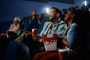 Young couple laughs while watching comedy movie in cinema.