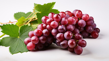 Fototapeta premium Isolated green-leafed, partially-cut red grapes on a white backdrop.