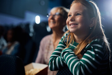 Happy little girl enjoying in movie projection in cinema.
