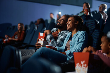 Happy black couple enjoying in movie projection in theater.