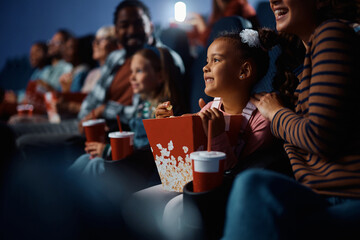 African American girl watching movie with her family in cinema.