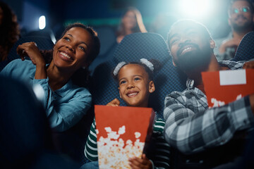 Obraz premium Happy African American family enjoys in movie projection in theater.