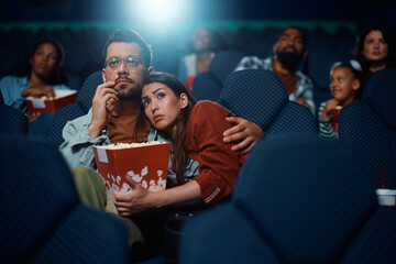 Young woman embracing her boyfriend while watching movie in cinema.