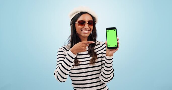 Green screen, phone and woman face with hand pointing in studio for fashion, sale or wow news on blue background. Smartphone, space and portrait of lady model show clothes discount, sign up or promo