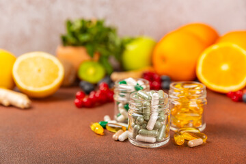 Vitamins and supplements. Variety of vitamin tablets in a jar on a texture background.Multivitamins with fresh and healthy fruits.Food supplements. Flat lay. Space for text.Copy space