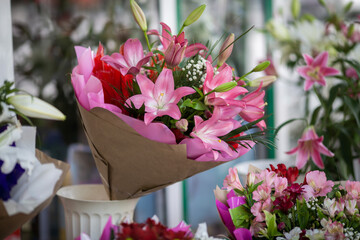 Pink bouquet of lilies on the stand in the flower shop. Showcase. Floral shop and delivery concept. Flowers market on the street. Many lilies flowers growing in pots for sale in florist's shop.