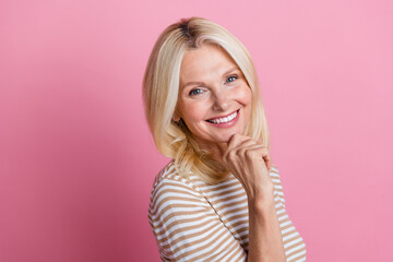 Portrait of toothy beaming woman with stylish hairdo wear trendy clothes holding fingers on chin isolated on pink color background