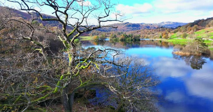 Beautiful clouds reflecting in the Rydal waters behind naked tree branches of the Autumn. 