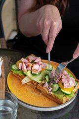 Girl cuts waffles with salad, ham and cheese