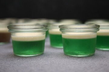 Wackelpudding, Götterspeise grün im Glas mit heller Sauce