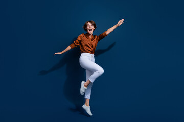 Fototapeta na wymiar Full length photo of carefree sweet lady wear brown shirt glasses jumping high having fun isolated blue color background