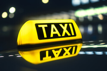 Selective focus on yellow taxi sign. Reflection in roof of car against neon lights of city street at night..