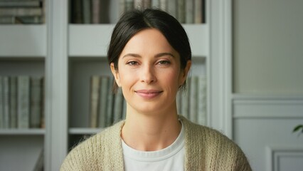 Portrait of a beautiful smiling confident young woman posing alone at home in office. European woman standing indoor smiling looking at camera. Happy casual lady with pretty face. Close up