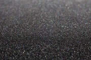 Black foam rubber. Closeup full-frame macro background with selective focus and shallow depth of field.