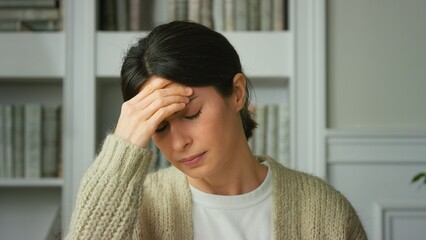 Young beautiful brunette woman suffering from headache at home. Tired overworked lady. Headache,...