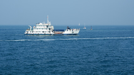 Panoramic view of a white ship (working barge) in the Adriatic Sea. Several sailing yachts in the background. Copy space.