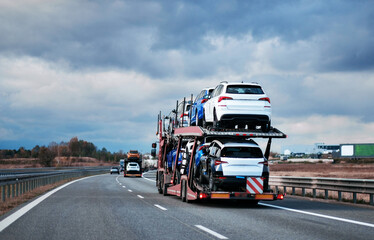 Car carrier trailer truck with brand new sedan-type cars for sale. New car delivery. Car...