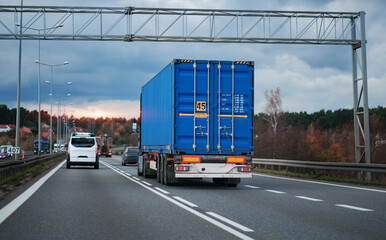 A cargo truck with a standard twenty-foot container on a motorway. Shipping of the goods in...
