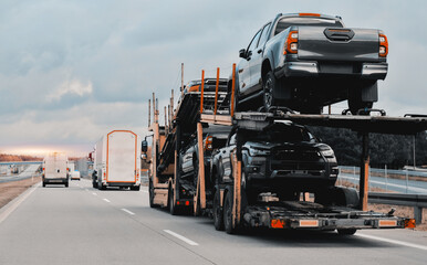 Car carrier trailer truck with brand new SUV cars for sale. New car delivery and shipping. Car transporter trailer loaded with many new cars for the customers. Two-level modular hydraulic semi-trailer - obrazy, fototapety, plakaty