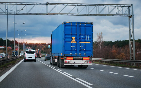 A cargo truck with a standard twenty-foot container on a motorway. Shipping of the goods in containers. Container carrier on a European highway driving in the right lane.