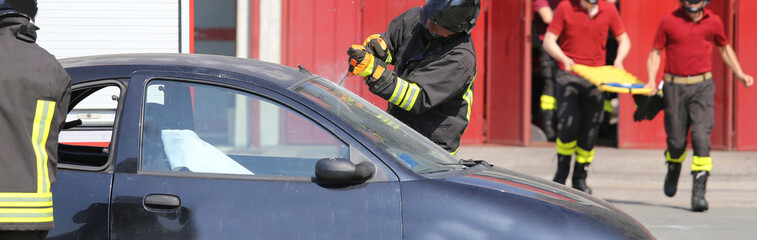 firefighter with special glass cutting hacksaw while removing the windshield to free the injured...