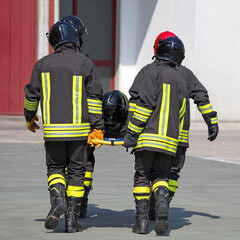Firefighters in uniform with protective helmet while transporting the injured person after the...