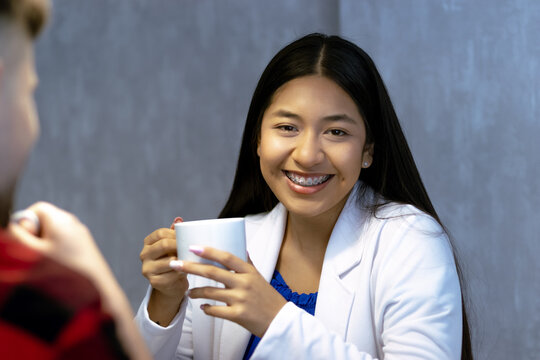 Formally dressed ethnic young woman looks into the camera with cup of coffee in hand.