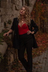 Beautiful  woman walking in the street of the city. Blond with curly hair fashion model wears stylish clothes, black blazer, fashion accessories