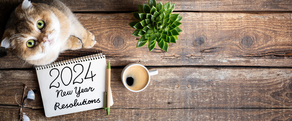 New year resolutions 2024 on desk. 2024 resolutions list with notebook, coffee cup, cute cat on table. Goals, resolutions, plan, cozy, hygge concept. New Year 2024 template, copy space