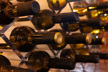 wine bottles filled with the best wine arranged in the cellar with a view of the black and gold...
