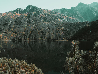 Where the river whispers over stones, harmonizing with the majestic backdrop of distant mountains.