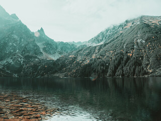 Where the sky kisses the peaks, a tranquil lake cradles the essence of mountain majesty.