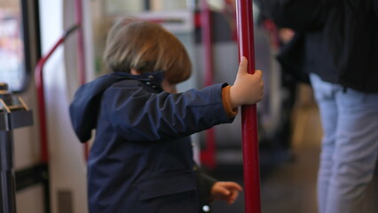Child holding into train metal vertical bar turning in circles to pass the time while traveling...