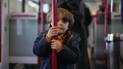 Child holding into train metal vertical bar turning in circles to pass the time while traveling commute