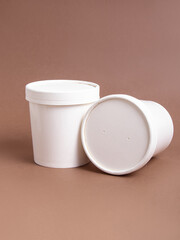 White disposable soup tureens with a lid on brown background. Disposable eco tableware. Cardboard...