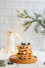 Viennese waffles with milk and blueberries on a white background