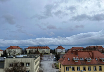Fototapeta premium Sky with beautiful clouds above buildings with tiled roofs. European town.
