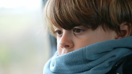 Close-up child face wearing scarf inside train. portrait of a small caucasian boy traveling with warm clothes