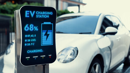 Futuristic clean energy utilization of smart EV charging station in residential area recharging electric car's battery. Technological advancement of high-tech EV car in modern city lifestyle. Peruse