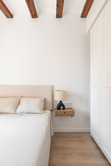 Wooden shelf with drawer and lamp by bed in stylish room