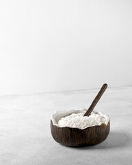 natural coconut flakes in the bowl of shape of coconut with spoon, vertical copy space