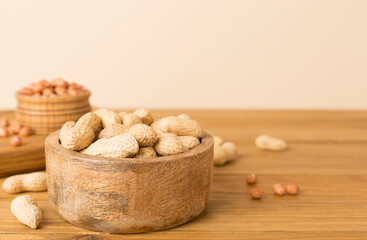 Peeled and unpeeled peanuts on wooden table