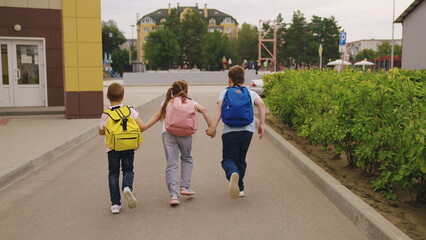 Junior schoolchildren with schoolbags walk together after school lessons
