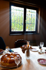 Christmas bread, candle, tree and glasses for wine.Orthodox Christmas on a table sunbathing with sunshine
