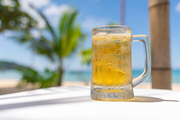 Photo of a iced cold beer on a table by the beach