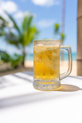 Photo of a iced cold beer on a table by the beach