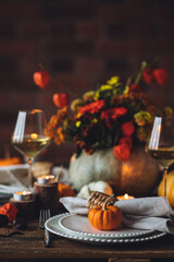 Obraz na płótnie Canvas Elegant atmospheric beautiful dinner table setting for thanksgiving or wedding celebration, fall countryside style, pumpkins as decor. Romantic cozy home atmosphere. Wine, floral pumpkin centrepiece.